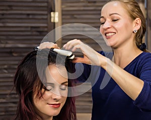 Elegant woman in beauty saloon. Hairdresser does coiffure in the form of big curl. Concept wedding hairstyle