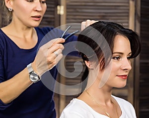 Elegant woman in beauty saloon. Hairdresser does coiffure in the form of big curl. Concept wedding hairstyle