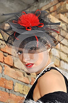 Elegant woman in black dress and hat with veil.