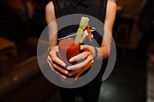 Woman holding a glass of alcoholic cocktail Bloody Mary indoors