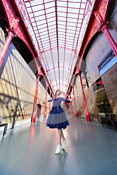 Elegant woman in blue long flying dress posing at stairway against old city building