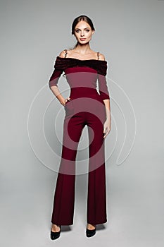 Elegant woman in bordo overall with bare shoulders and high heels.