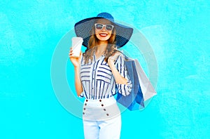 Elegant woman with coffee cup wearing a shopping bags, straw hat