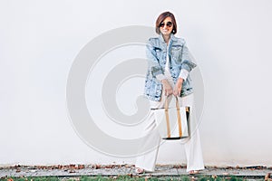 Elegant woman dressed in oversize denim jacket and wide white tr
