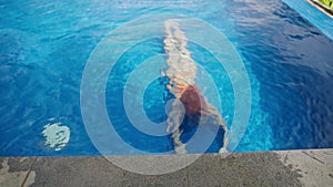 Elegant woman emerges from blue water in upscale infinity pool, tropical vibe. Luxe travel lifestyle, relaxation at