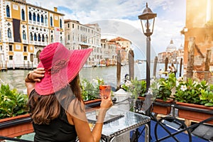 Elegant woman enjoys an aperitif sitting next to the Canale Grande