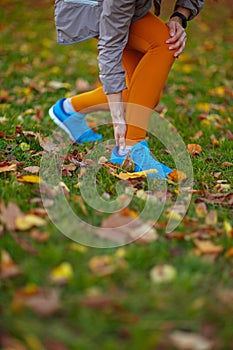 Elegant woman in fitness clothes in park having leg pain