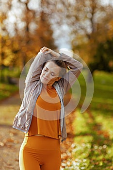 elegant woman in fitness clothes in park stretching