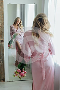 an elegant woman with flowers looks in the mirror in the room