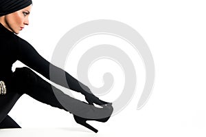 Elegant woman made up and dressed in black with turban and gloves on a white background with copy space