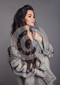 Elegant woman in mink fur coat isolated on gray studio background. Fashion Brunette Girl in Luxury Winter outerwear