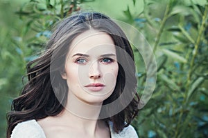 Elegant woman outdoor. Pretty brunette girl face on green spring background, natural beauty photo