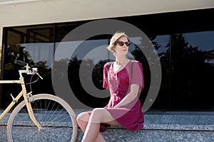 Elegant woman in polka dot dress sitting near a retro bike in ur