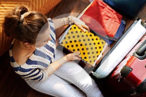 Elegant woman putting stuff in open travel suitcase