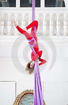 Elegant woman in red costume on aerial silk in a studio