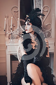 Elegant woman in retro style of the 20s, lady flapper in a black dress, dark hair and a bandage, feather boa, long