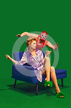 Elegant woman in robe holding cocktail with wrestler in dynamic pose behind her. against vibrant green background.