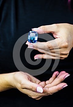 Elegant woman`s hands hold a large deep blue topaz stone