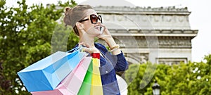 Elegant woman with shopping bags using mobile on Champ Elysees