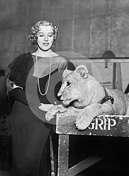 Elegant woman standing next to a lion