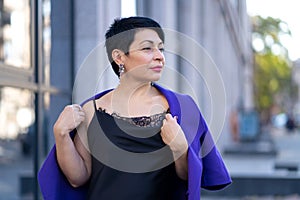 An elegant woman in a stylish outfit poses on a city street