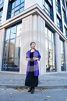 An elegant woman in a stylish outfit poses on a city street