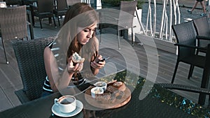 Elegant woman texting on smartphone and eating a muffin