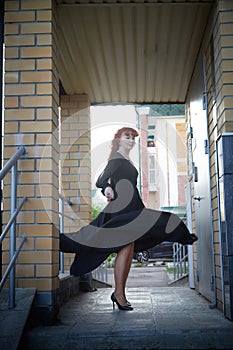 Elegant Woman Twirling in Black Dress on Staircase. A woman in a twirling black dress captured mid-movement on the porch