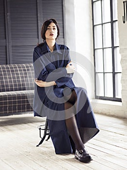 Elegant woman wearing denim suit sitting in studio