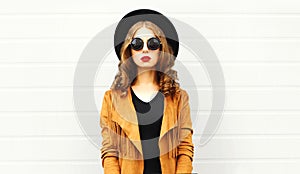 Elegant woman wearing a retro elegant hat, sunglasses, brown jacket