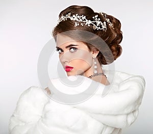 Elegant woman in white fur coat. Wedding Hairstyle. Beautiful fa