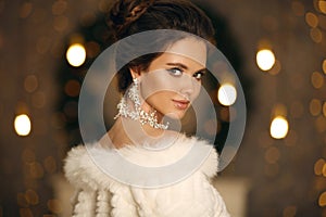 Elegant woman in white fur. Winter fashion portrait of Beautiful bride young with diamond earrings and necklace jewelry set.