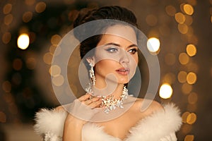 Elegant woman in white fur. Winter fashion portrait of Beautiful bride young with diamond earrings and necklace jewelry set.