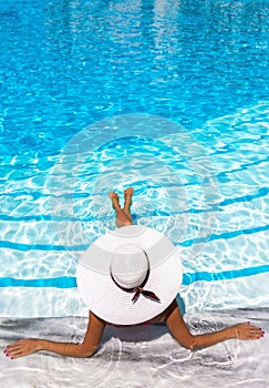 Elegant woman with white hat enjoys the pool