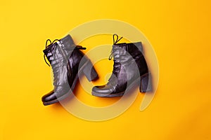 Elegant women black heeled boots. Top view of black boots on a yellow background.