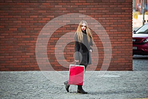 Elegant young beautiful women holding shopping bags, walking away from shop. Sale, consumerism and people concept