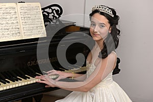 Elegant young brunette with oriental appearance in a white dress at the piano