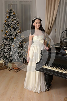 Elegant young brunette with oriental appearance in a white dress at the piano