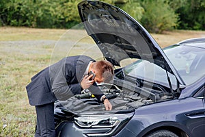 Elegant young business man trying to fix car breakdown or engine failure