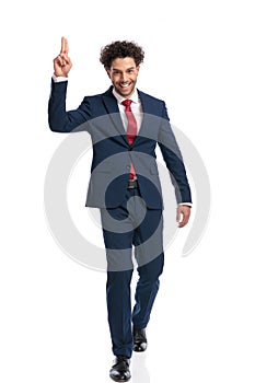 Elegant young businessman holding fingers up, smiling and walking