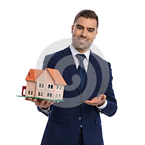 Elegant young businessman in navy blue suit recommending house model photo