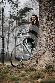 Elegant young businesswoman with a stylish bicycle in an urban park