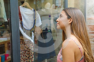 Elegant young fashion woman looking at showcase of clothing store