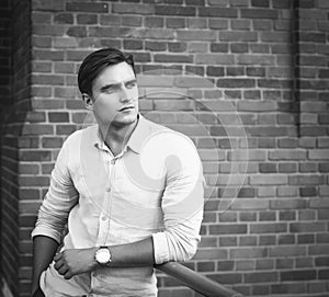 Elegant young handsome man posing over brick wall. Fashion portrait