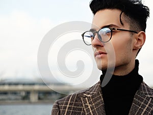 Elegant young handsome man wearing eyeglasses. Outdoors fashion portrait.