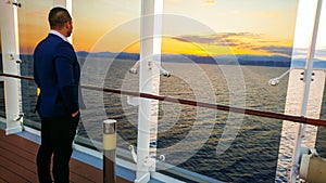 An elegant young man in front of a beautiful sunset. A man on a journey admires a beautiful sunset at sea on a cruise liner