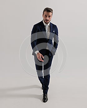 elegant young man walking with hand in pocket and looking forward