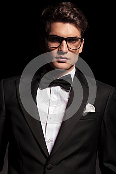 Elegant young man wearing a tuxedo and glasses.