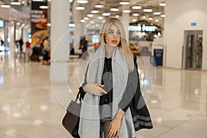 Elegant young modern woman blonde in a luxurious stylish coat with a vintage gray fashionable scarf