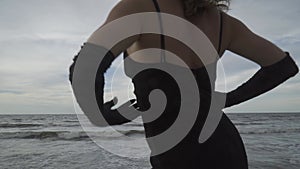 elegant young woman in black dress and long gloves on the pier. Vacation, freedom, enjoy concept